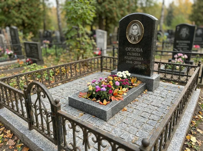 Благоустроенное захоронение с гранитной плиткой, оградой и цветником в Новом Уренгое