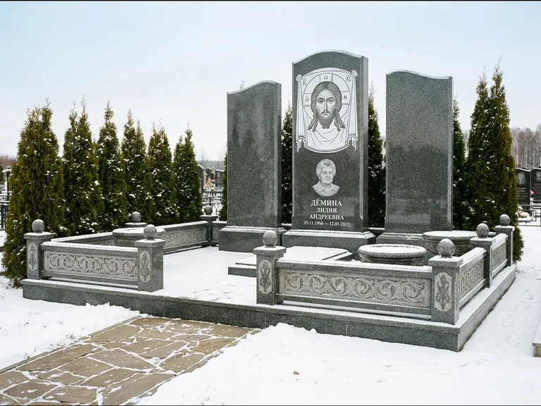 Памятник с гравировкой иконы: узкая вертикальная стела-пилон с ликом — икона в резной рамке-киоте, открытая лужайка без ограды, работа «Одинцов» в Новом Уренгое