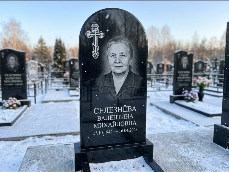 Памятник из чёрного гранита — массивная стела с крестом в лучах с крестом в лучах, работа «Одинцова» в Новом Уренгое